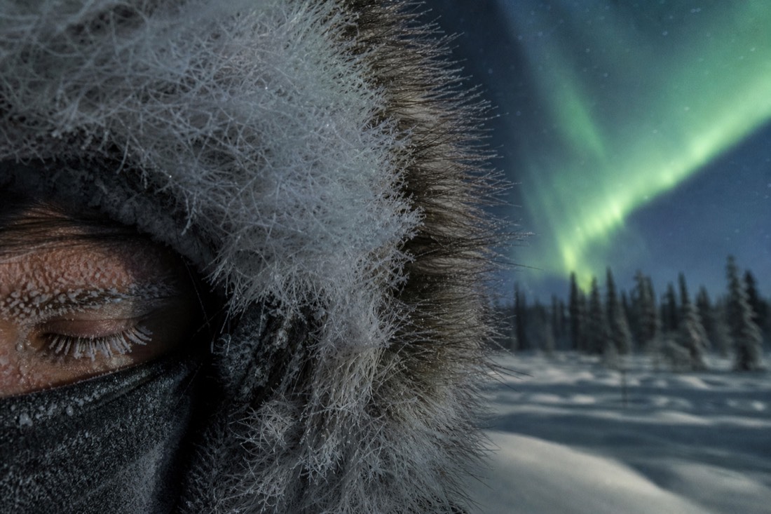 Close view of frost forming on a person's eyelashes and parka hood fur in extreme cold