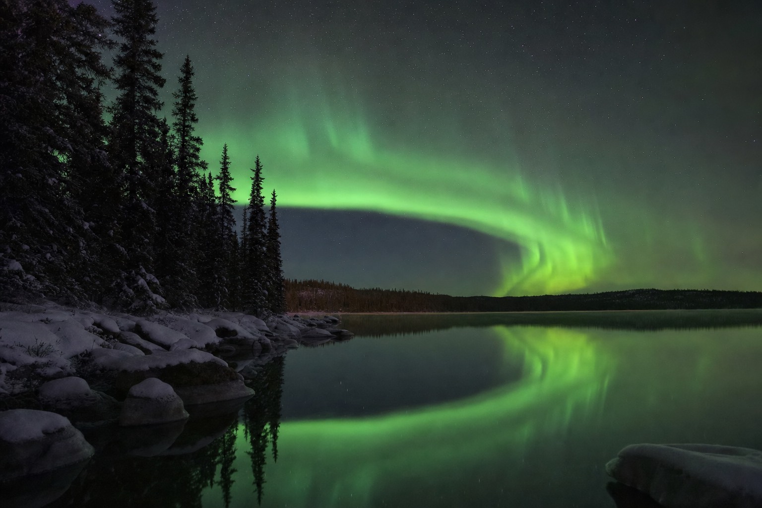 Green aurora reflected in a mirror-calm lake near Yellowknife on a September night before freeze-up