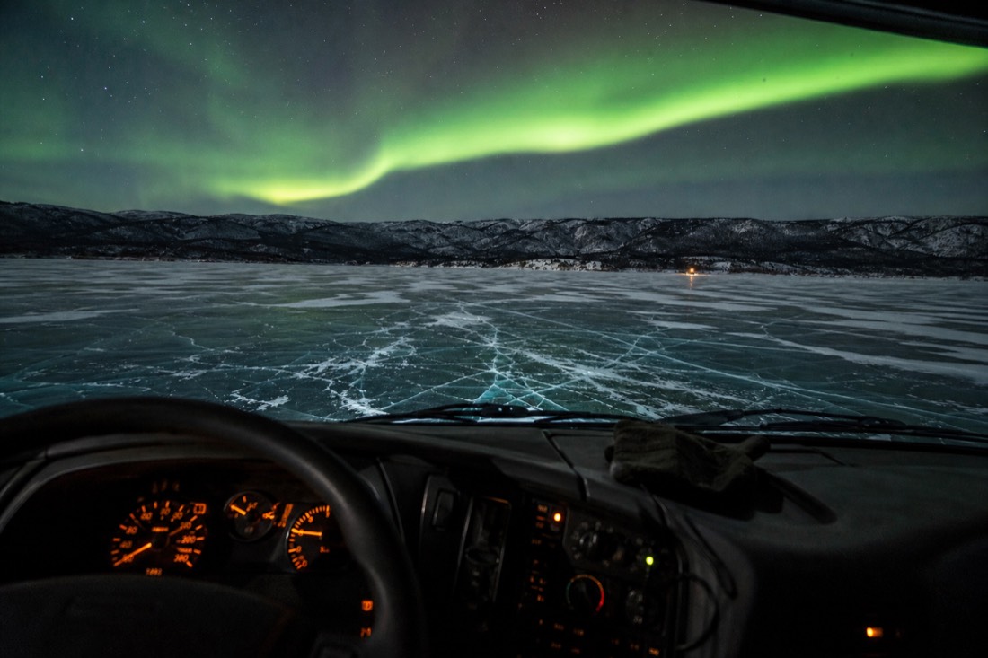 Film-style dramatic view of a truck cab interior looking out over a cracking frozen lake surface