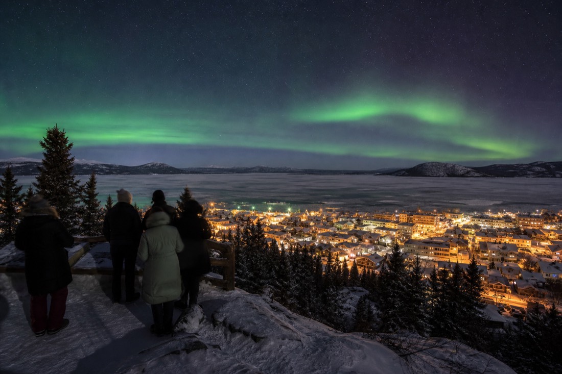 Small group at the Bush Pilots Monument viewpoint looking over Old Town rooftops and the frozen bay
