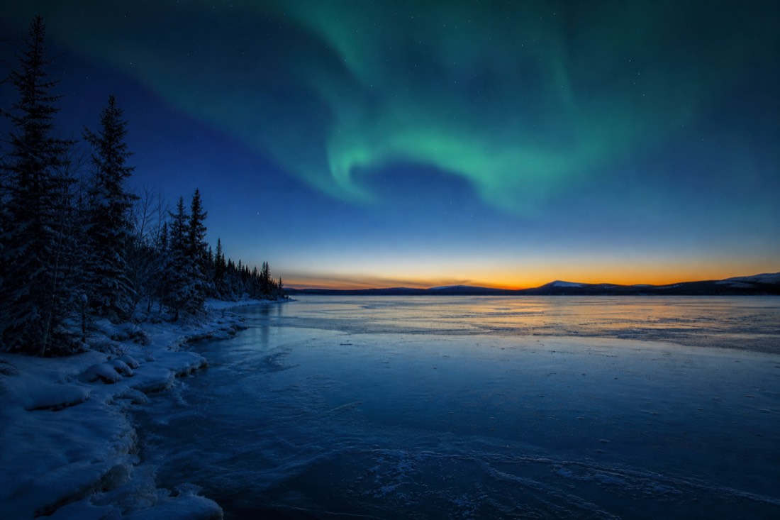 Deep blue twilight over a frozen subarctic lake with the last band of daylight on the southern horizon
