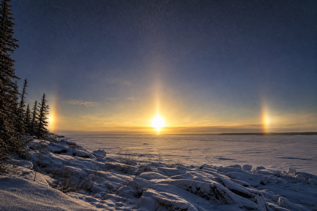 Sun dogs flanking a low winter sun over the frozen expanse of Great Slave Lake