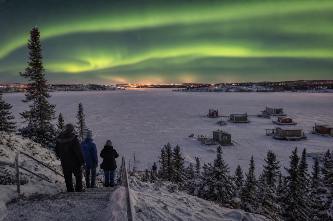 Visitors on the Bush Pilots Monument stairs overlooking houseboats frozen into Yellowknife Bay