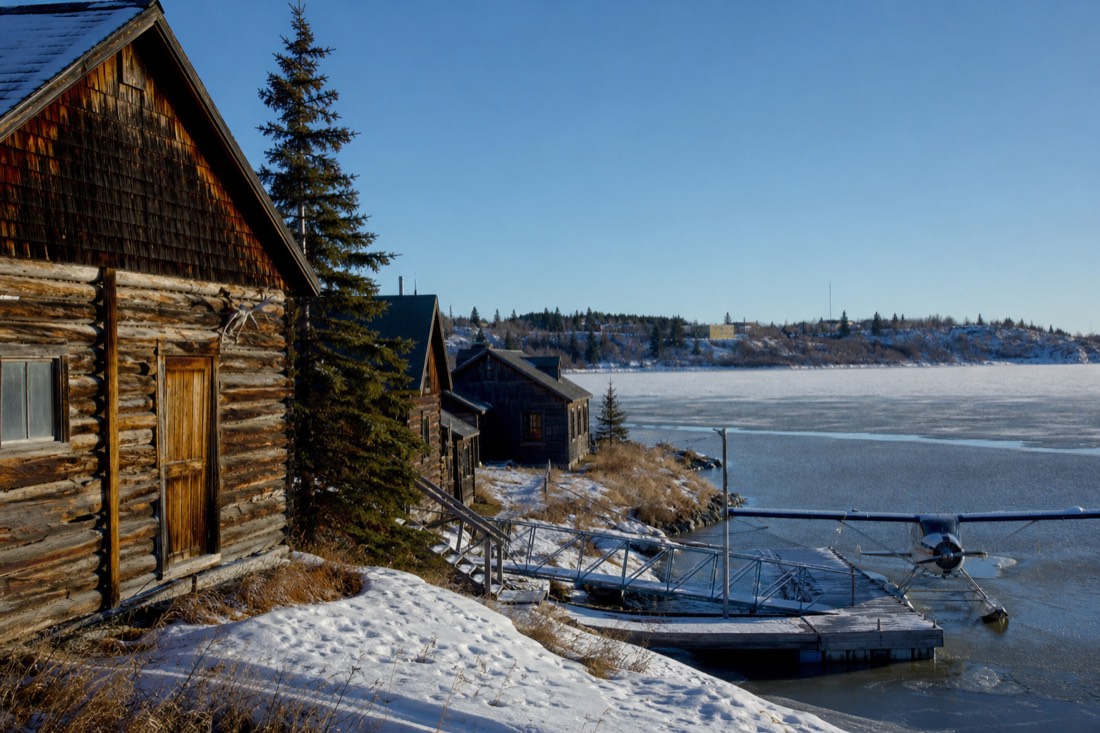 Weathered gold-rush era cabins and a float plane dock in Old Town Yellowknife on a clear cold day