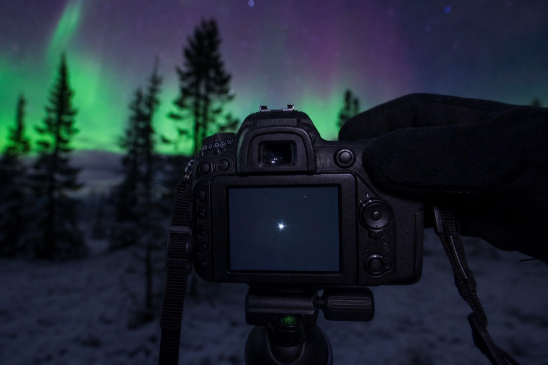 Magnified live view on a camera screen showing a single bright star being brought to a fine point during manual focusing