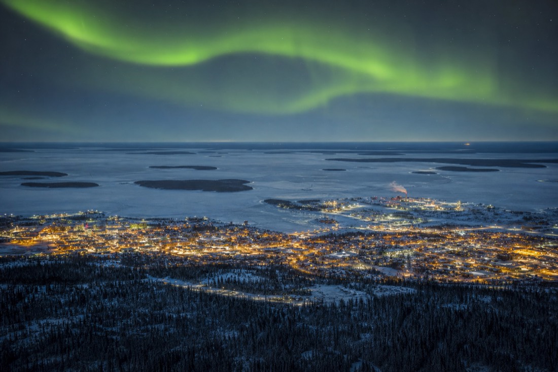 Aerial view of Yellowknife between spruce forest and the vast frozen expanse of Great Slave Lake
