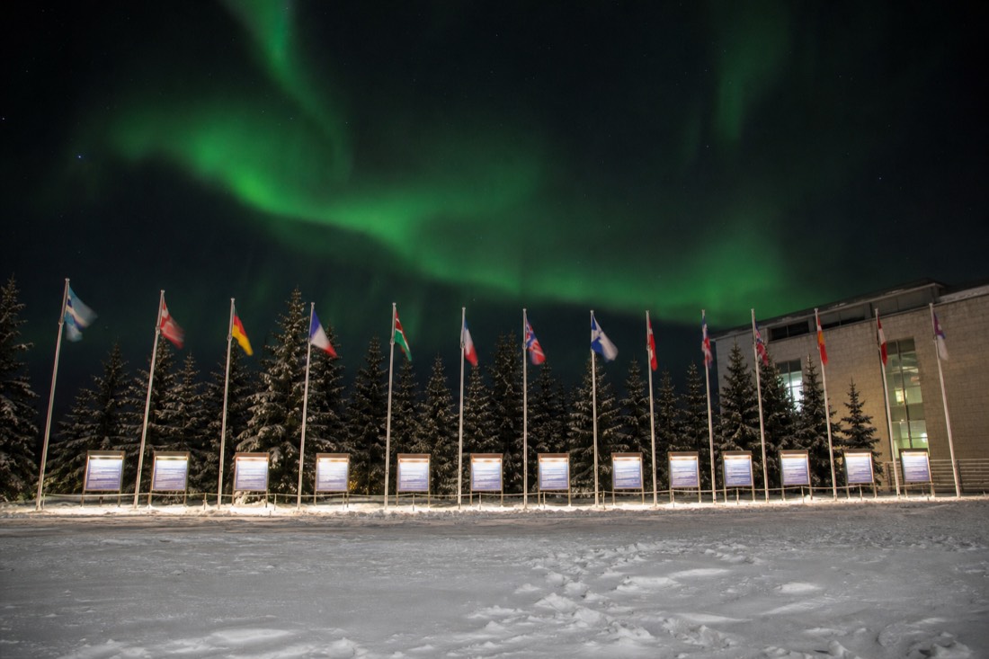 Row of eleven flags and language panels outside a government building in the northern capital