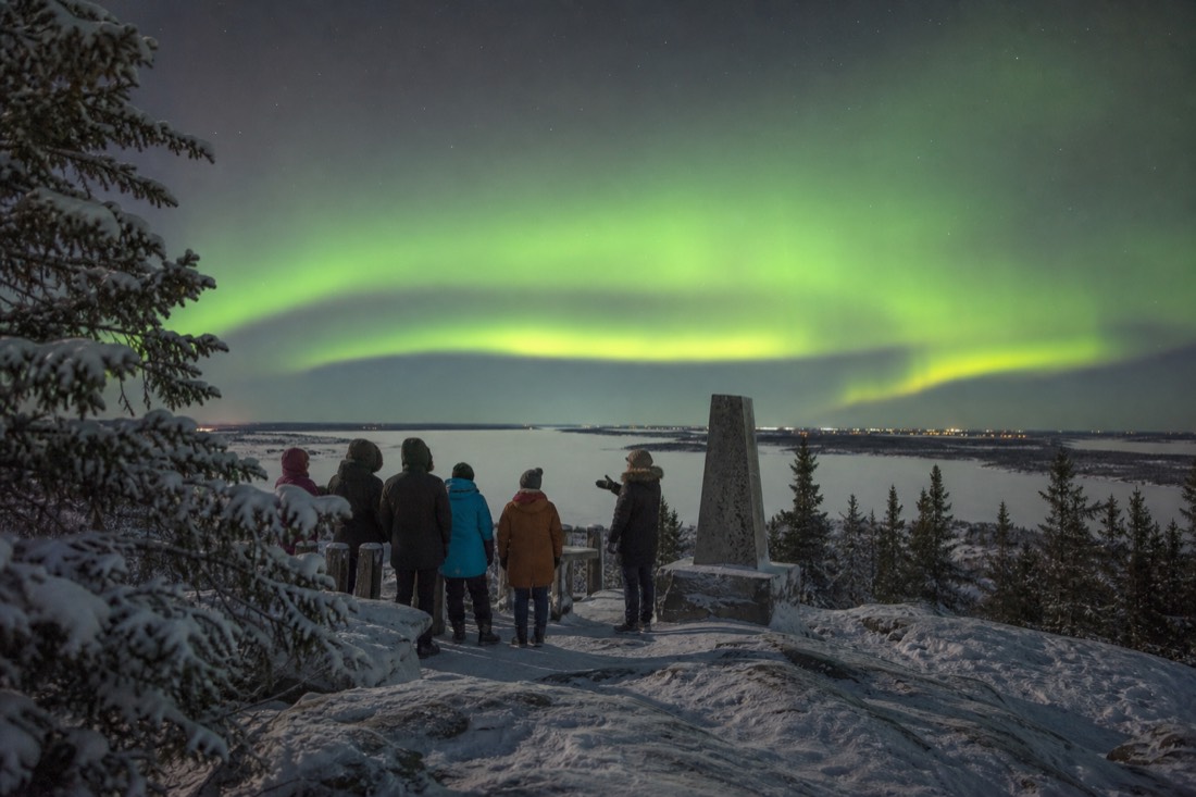 Small tour group listening to a guide at the Bush Pilots Monument lookout above Yellowknife Bay