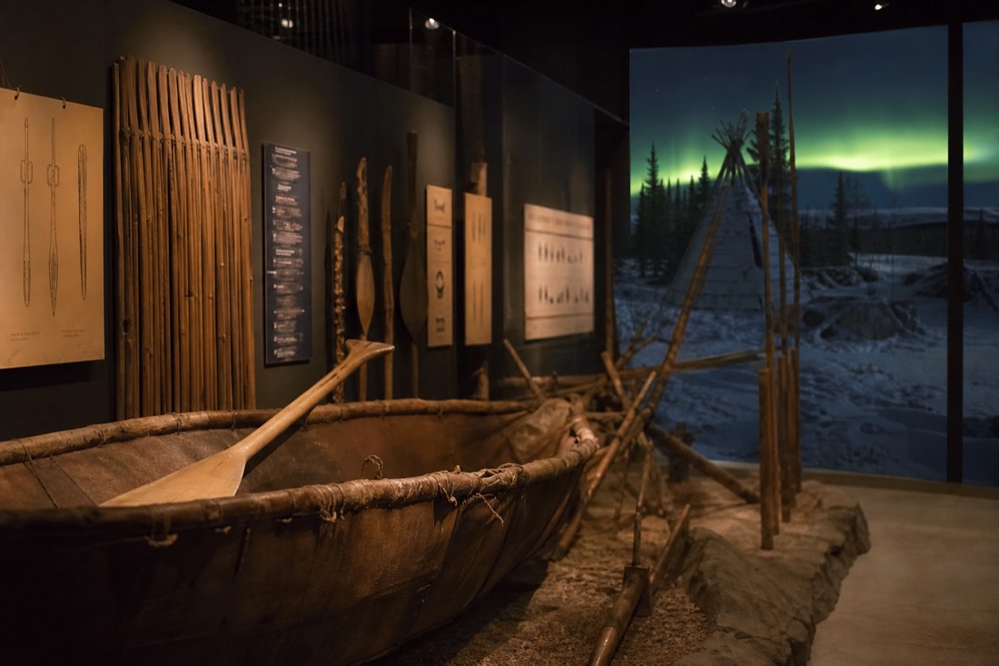 Museum exhibit of northern Indigenous tools and language panels under soft gallery lighting