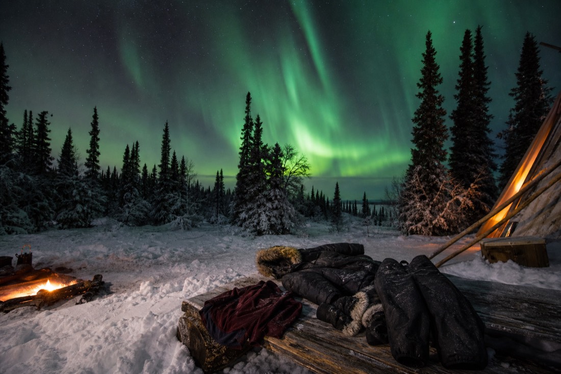 Winter clothing layers laid out on a bed: thermal base, fleece, down parka, insulated pants, boots and mitts