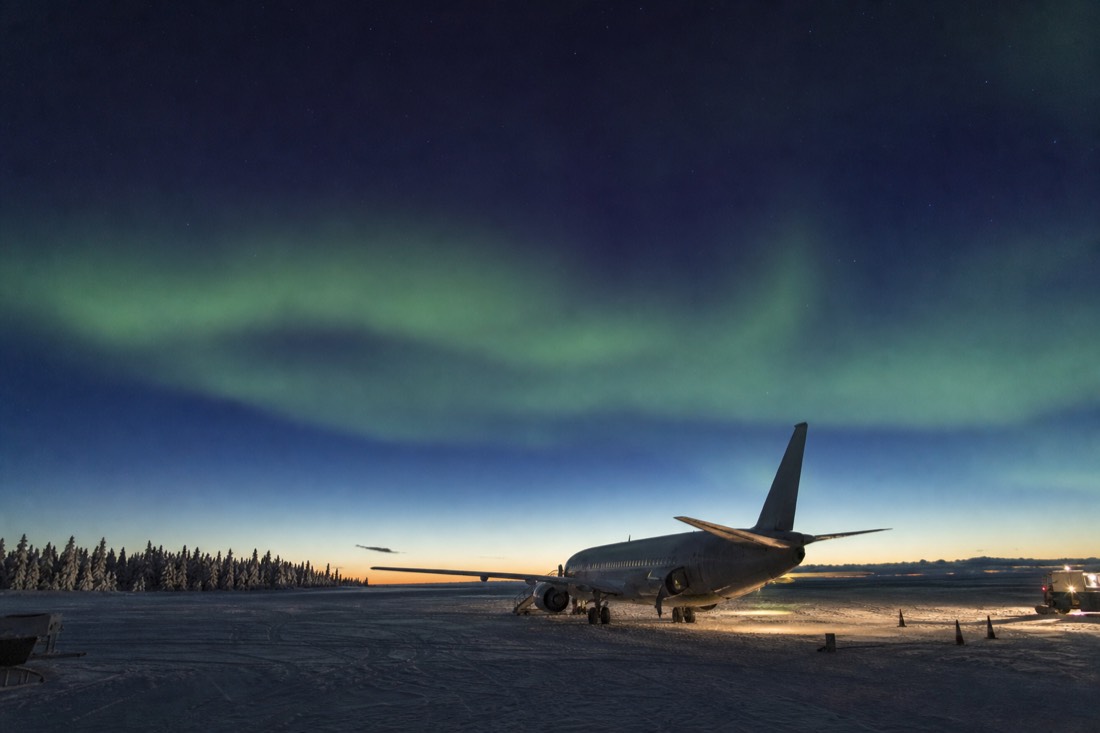 Passenger jet parked on the snowy apron of Yellowknife airport under a clear cold sky