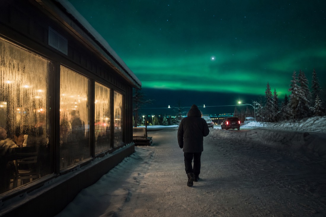 A person in a heavy parka walking past steamed-up restaurant windows on a frigid Yellowknife evening