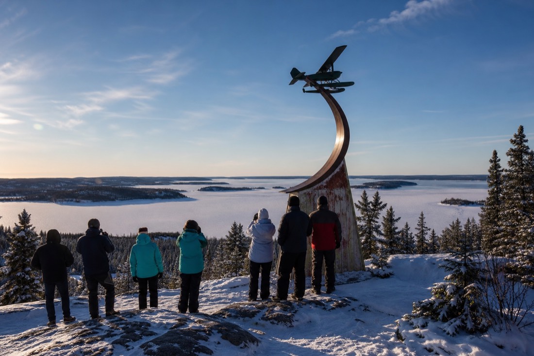 Small tour group at the Bush Pilots Monument viewpoint overlooking Yellowknife Bay on a clear summer day