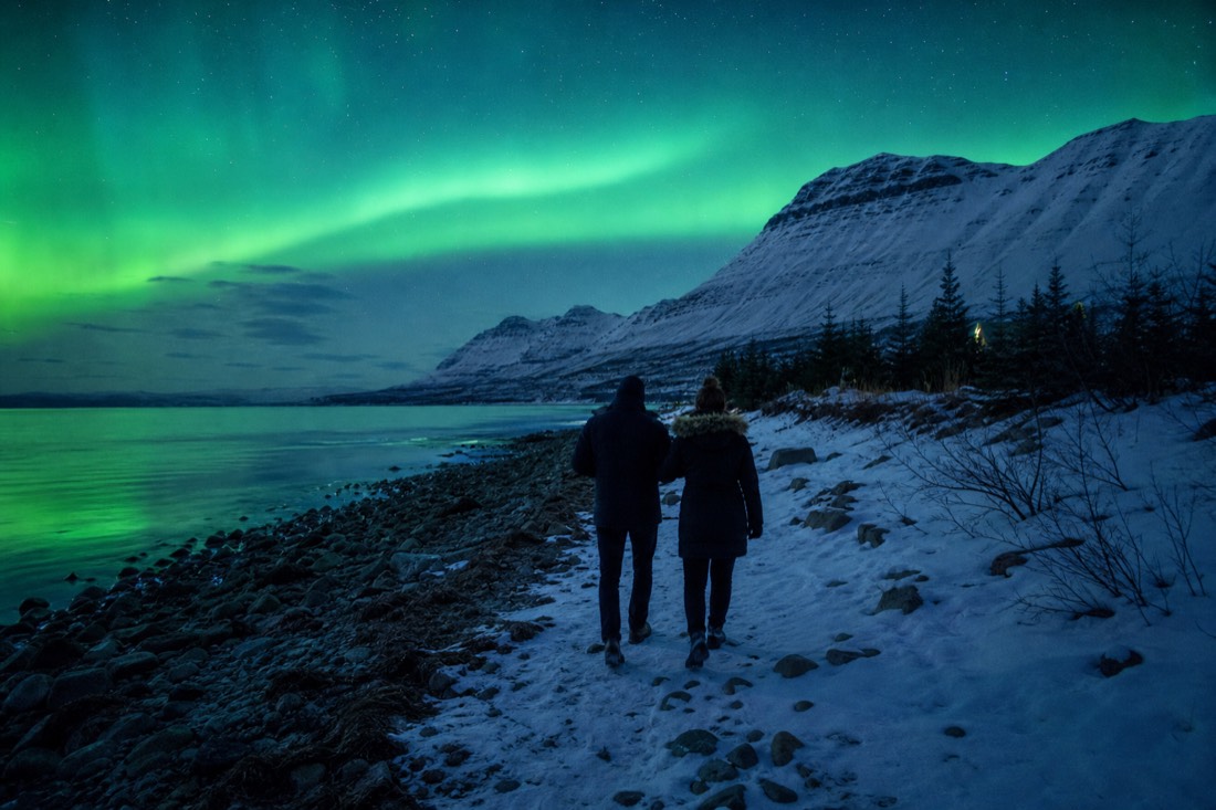Couple walking the Old Town shoreline at midnight under a bright twilight sky in midsummer