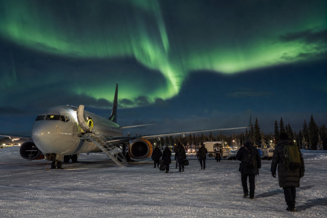 Jet on the snowy apron at Yellowknife airport at dusk with passengers walking across the tarmac in parkas