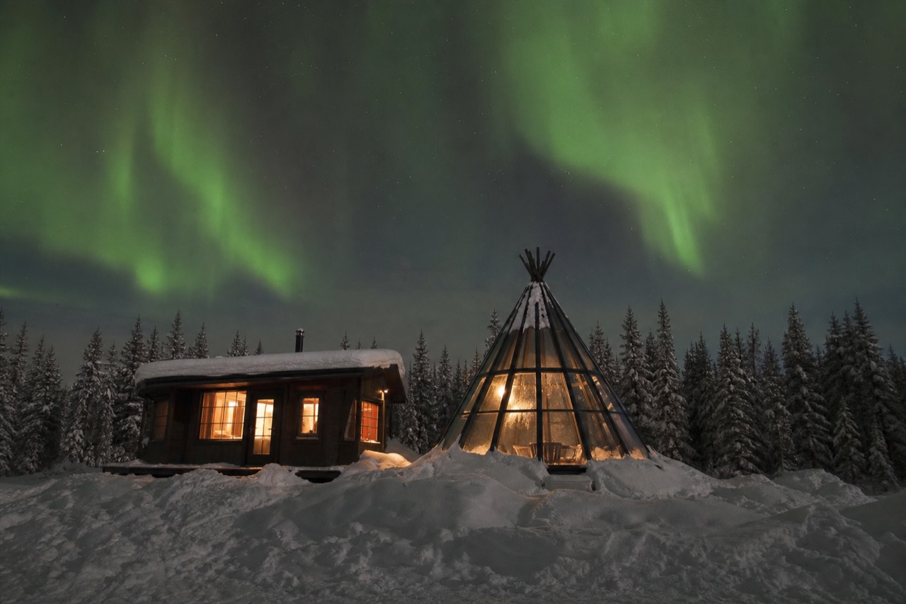 A heated viewing cabin and glass tipi under dancing northern lights outside Yellowknife